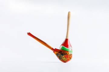 A wooden spoon with a floral ornament in the traditional Russian folk style and a Mexican maracas with a traditional pattern on a white background. To advertise the Russian-Mexican cuisine.