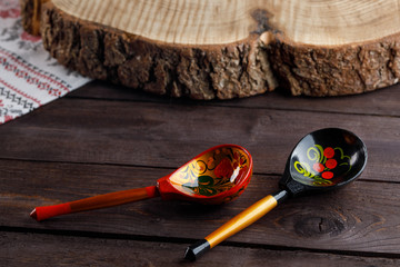 Bright and beautiful Khokhloma painted wooden utensils. Two wooden spoons with a traditional Russian pattern on a wooden background.