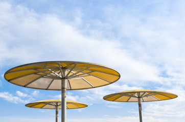 Obraz na płótnie Canvas Three yellow parasols against blue sky