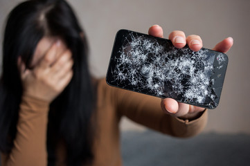 Unhappy woman holding broken smartphone.