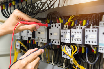 Electricians hands testing current  electric in control panel.