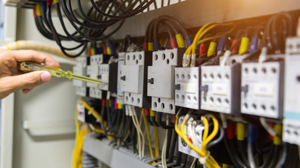 Electricians hands testing current  electric in control panel.