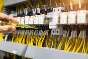 Electricians hands testing current  electric in control panel.