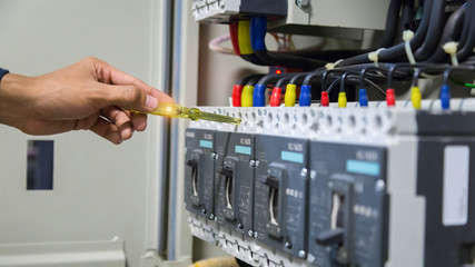 Electricians hands testing current  electric in control panel.