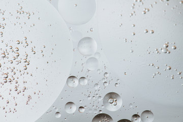 Macro shot of backlit water-oil emulsion over colored background.