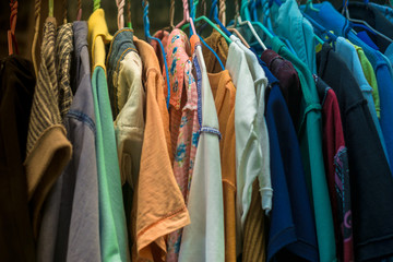 Multi used colorful clothes shirt with hangers in wardrobe.