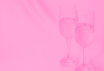 two glasses of champagne on background of fabric. pink toned