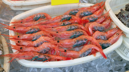 A tray of fresh red japanese shrimps with many tiny black eggs in their abdomen.