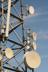 Close up of several dish antennas on a lattice telecommunications mast.