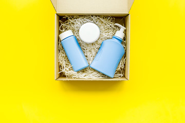 Delivery. Cardboard box with cosmetics on yellow background top view copy space