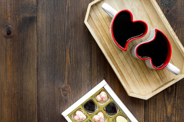 Dating on Valentine's day concept. Heart-shaped mugs and sweets on dark wooden background top view space for text