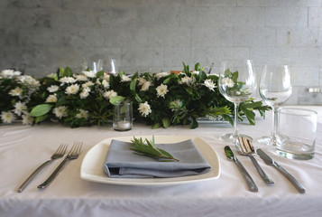 Dining set on the white table sheet with white bouquet flower background