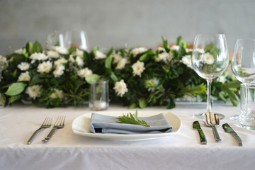 Dining set on the white table sheet with white bouquet flower background