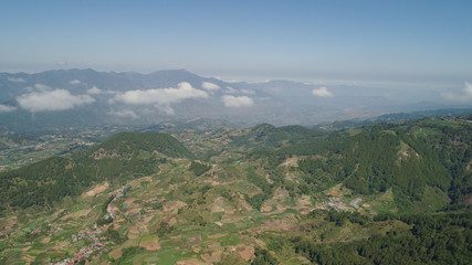 Aerial view of rice terraces and agricultural farm land on the slopes of mountains valley. Cultivation of agricultural products in mountain province. Mountains covered forest, trees. Cordillera region