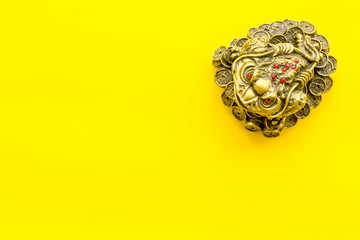 Buddhist symbol. Oriental three legged toad with gold coins on yellow background top view copy space
