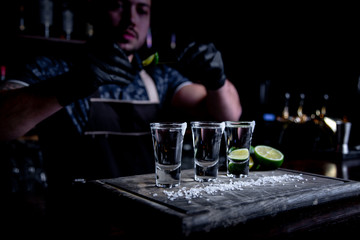 aperitif with friends in the bar, three glasses of alcohol with lime and salt for decoration. Tequila shots, selective focus