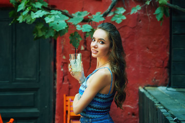 Fototapeta premium Portrait of a young woman with a glass of soft drink in a cafe