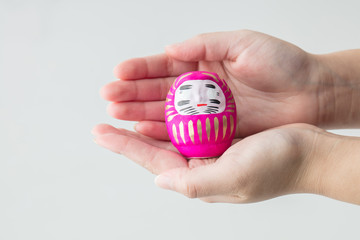 白背景で1つのだるまを両手で持つコピースペース