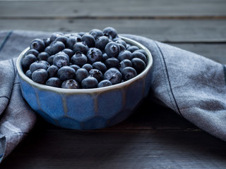 Bluelerry in ceramic bowl on wood floor.