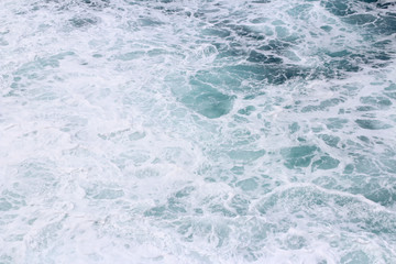 Splashing sea water with foam and bubbles at Timang Beach in sunny day, Yogyakarta, Indonesia