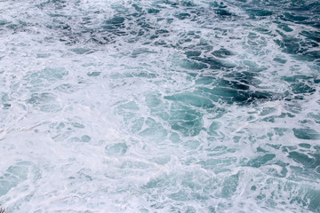 Splashing sea water with foam and bubbles at Timang Beach in sunny day, Yogyakarta, Indonesia
