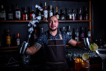 The barman juggler throws up an ice for cocktail at bar