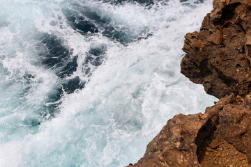 Close-up of natural rock formation with the wave at Timang Beach in sunny day, Yogyakarta, Indonesia