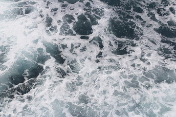 Splashing sea water with foam and bubbles at Timang Beach in sunny day, Yogyakarta, Indonesia