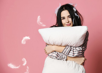 Beautiful brunette girl just woke up with soft pillow feathers and sleepy mask bandage for sleep 