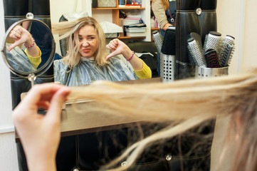 Unhappy young woman displeased with her hair and shows thumb down.