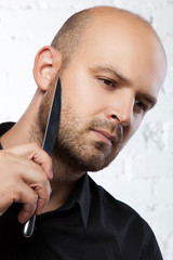 Man with knife shaving beard