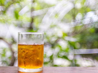 ice lemon tea on wood table with nature green blur bokeh background