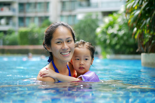 Asian Chinese Mother and Daughter bonding in the swimming pool smiling happy