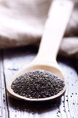 Raw Chia seeds in bamboo spatula on wooden table