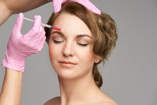Face needle injection. Young woman cosmetology procedure. Doctor gloves. Brow