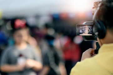 Cameraman recording video of young woman,  focus on camera screen.