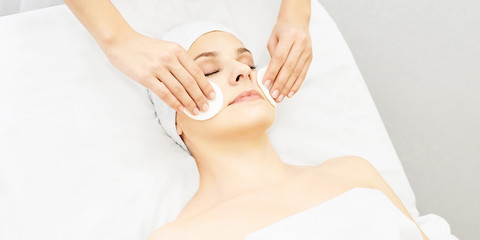 Cosmetology doctor remove mascara from girl face. Cotton pad with woman hands. Demakeup lotion