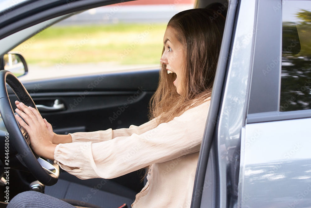 Wall mural Young woman in car. Ride instruction accident. Automobile loan