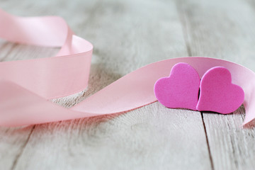 Two hearts and pink ribbon on white wooden boards. Valentines day, marriage, wedding, love concept. Close-up, objects, couple