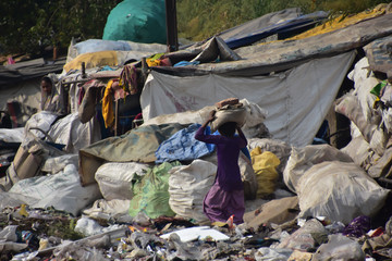 インドの首都のデリー　線路沿いのスラム　レンガを頭に乗せて運ぶ少女
