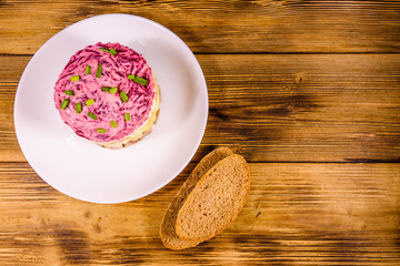 White plate with russian traditional new year salad herring under fur coat and rye bread on wooden table. Top view