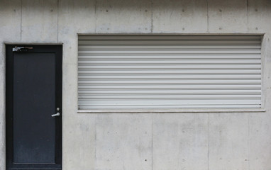 weathered metal dark door and shutter window on cement wall background.