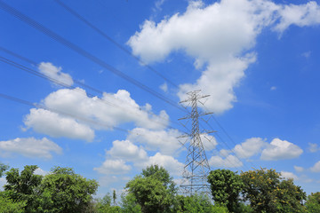 Obraz premium Electricity pylon of high-voltage power lines on green field with beautiful clouds on blue sky.