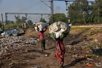 インドの首都のデリー　線路沿いのスラム　資源ごみを運ぶインド人女性