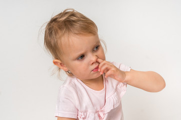 Baby girl is picking her nose with finger inside