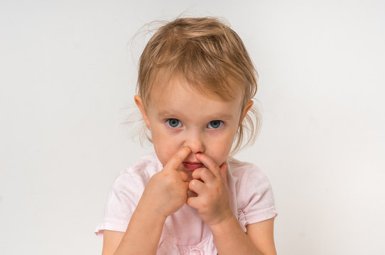 Baby girl is picking her nose with finger inside