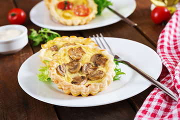 Mushrooms, cheddar tartlets on wooden background. Mini pies. Delicious appetizer, tapas, snack.