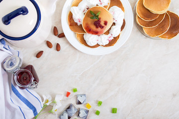 Delicious pancakes with raspberry jam and whipped cream on a white plate on the kitchen table. Classic American homemade breakfast.  The top view