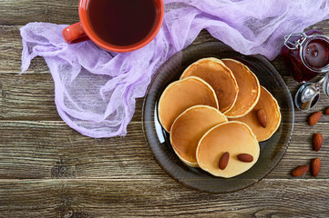 Delicious almond pancakes with tea and jam on a wooden table. Top view.