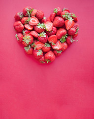 Heart shaped strawberry on ping background and copy space.